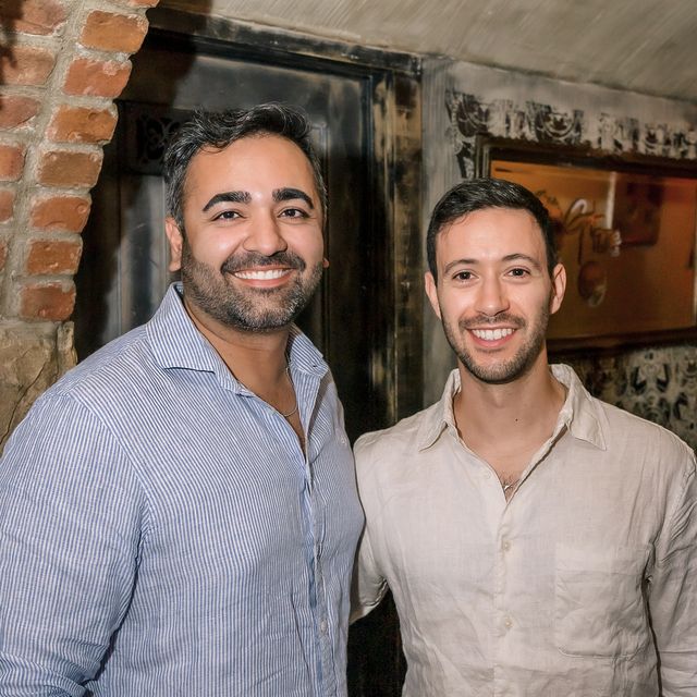 Two teammates at a team dinner in front of an exposed brick wall
