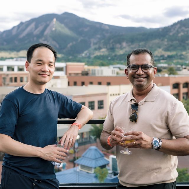 Two teammates with drinks on the deck above Boulder