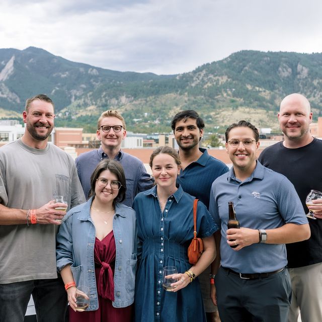 Teammates gathered outdoors with the mountains behind them