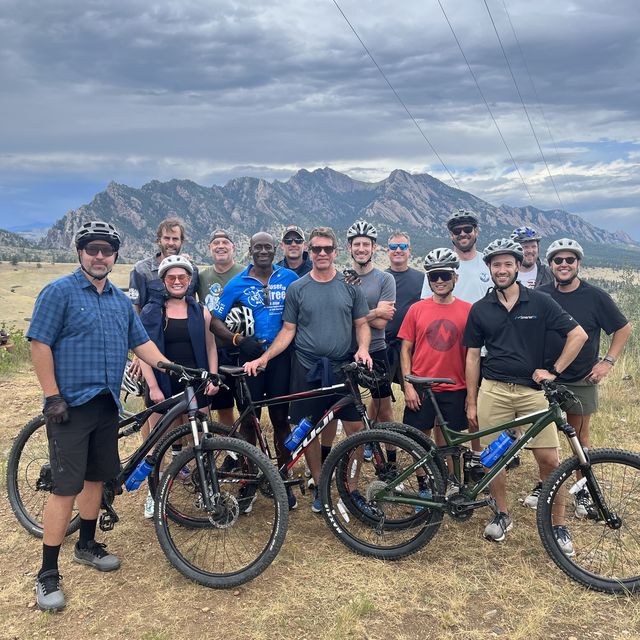 Teammates with mountain bikes in front of the Flatirons