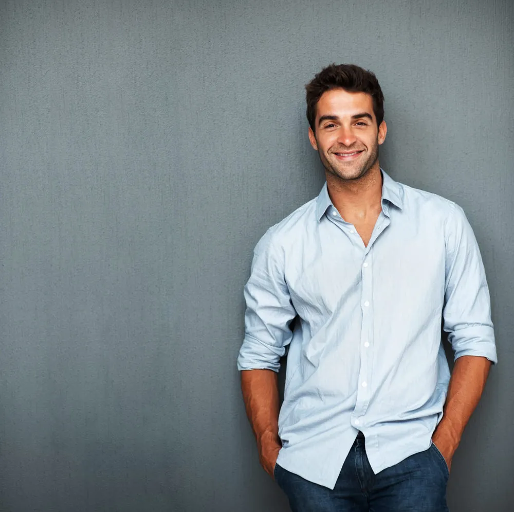 Homme souriant, confiant, appuyé contre un mur