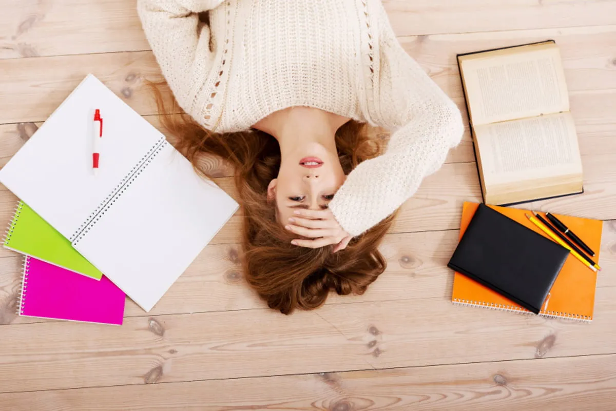 Étudiante allongée parmi ses cahiers, stressée par les examens