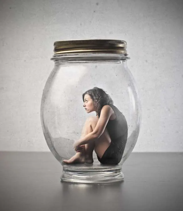 Femme recroquevillée dans un bocal de verre