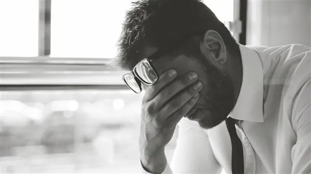 Homme la tête dans les mains, découragé, photo en noir et blanc