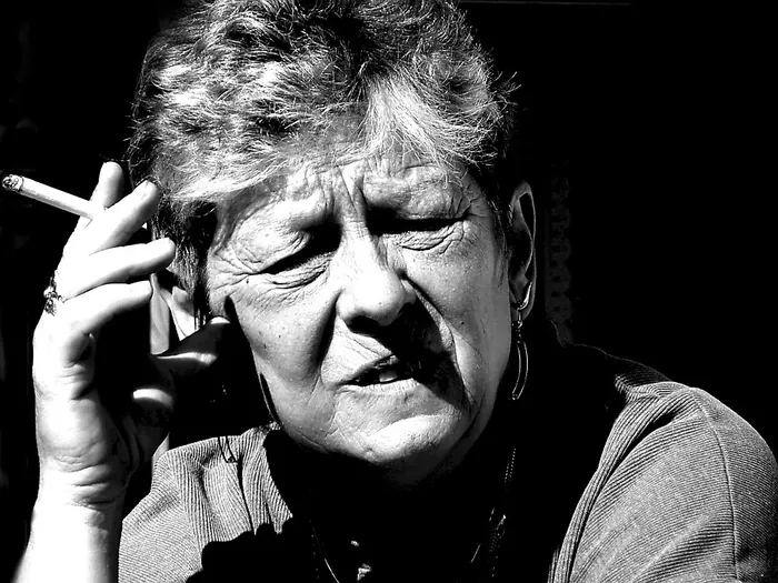 Femme âgée qui fume une cigarette, photo en noir et blanc