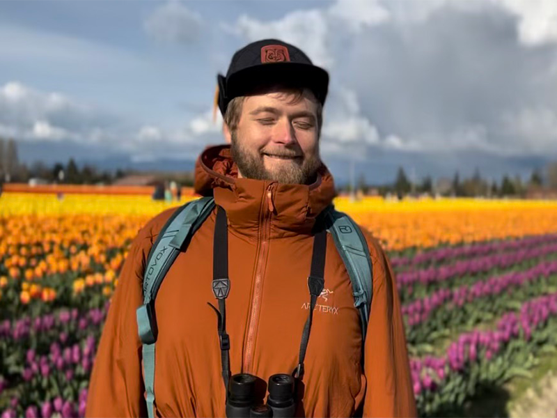 Photo of Brian standing in front of a field of brightly-colored tulips.
