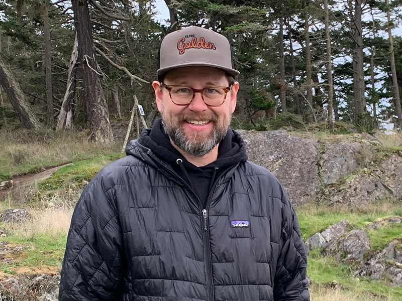 Photo of Tim. There is a forest in the background.