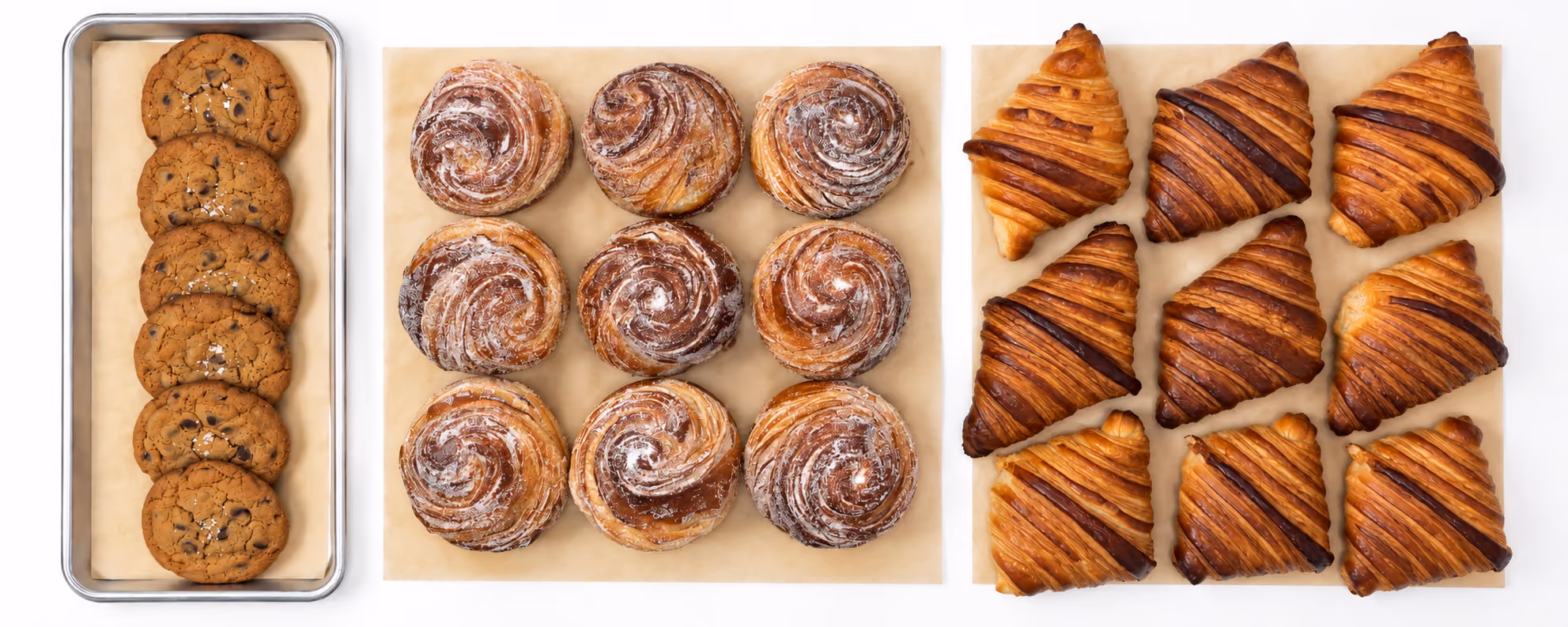 Trays of chocolate chip cookies, cinnamon rolls and croissants from Merci Bakery