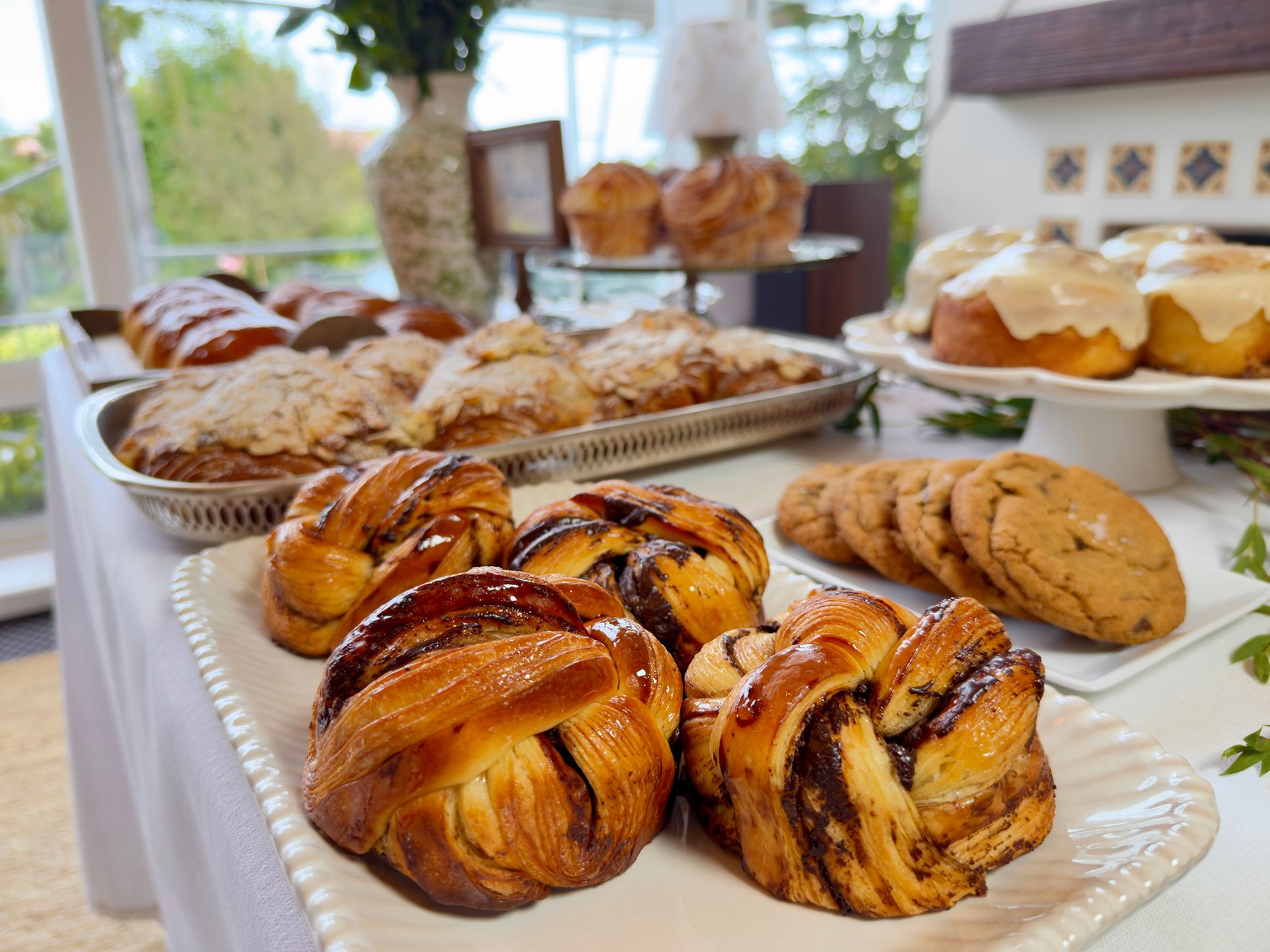 A table of chocolate brioche swirls, cookies and cinnamon rolls set out for an event