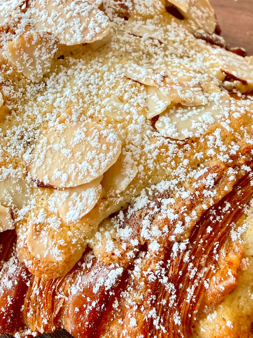 Close-up of an almond croissant topped with toasted almonds and powdered sugar