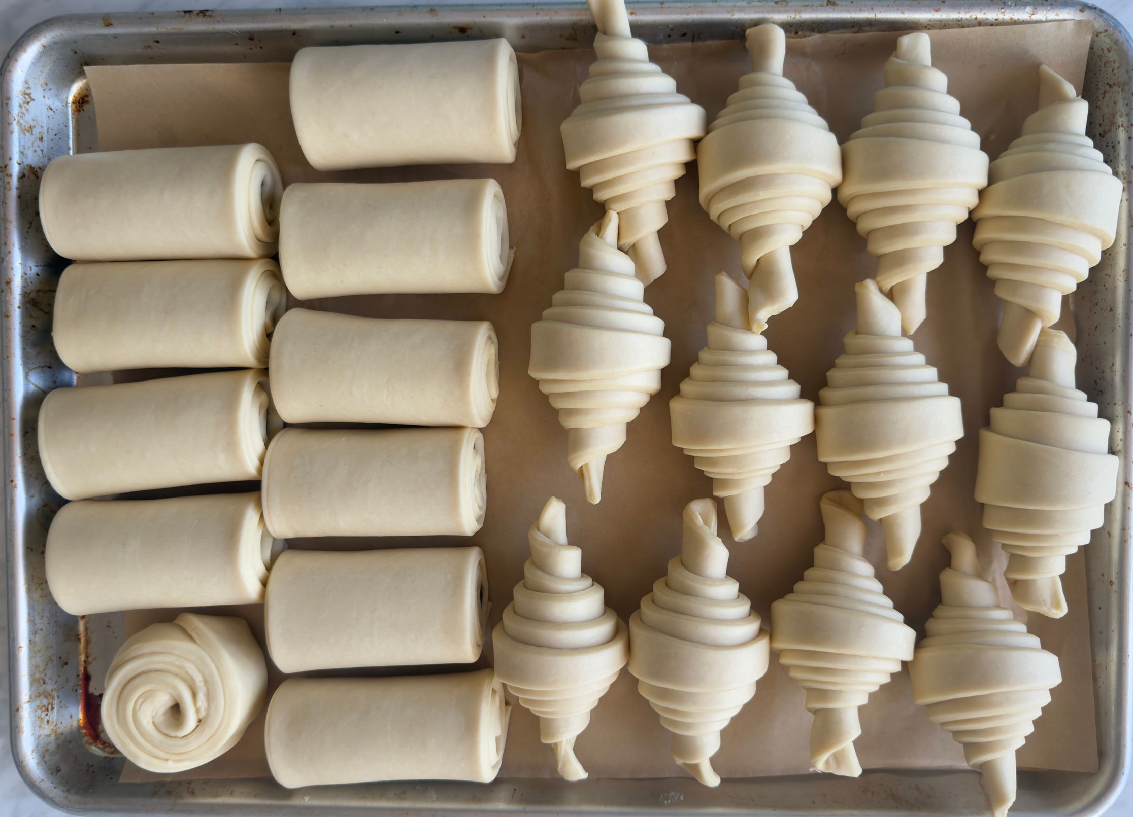 A tray of rolled dough and shaped croissants ready for their final proof