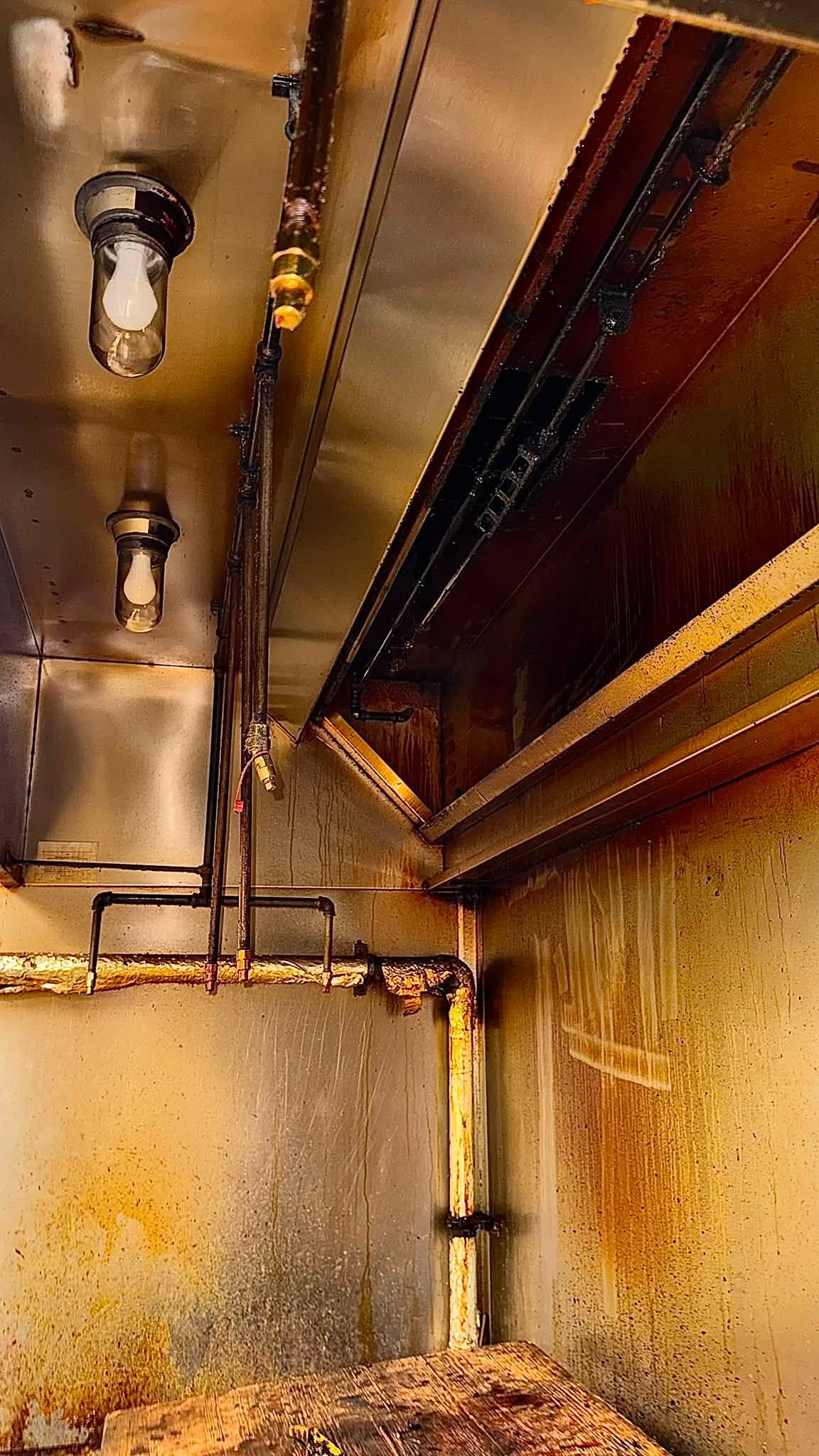 Intérieur d’une hotte commerciale avant nettoyage, avec accumulation de graisse.