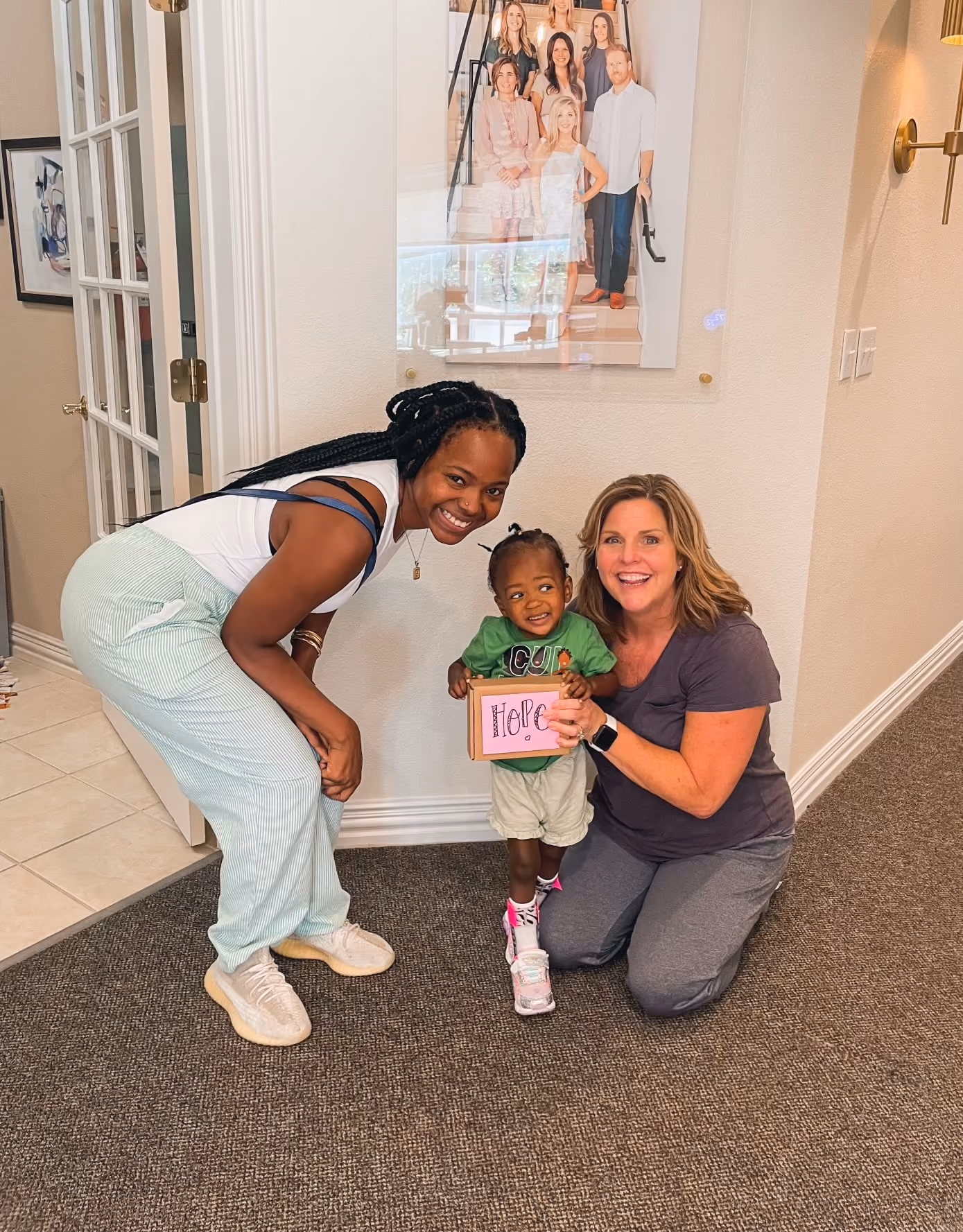 Hope holding a sign beside her mother Sarah Weaver and a KinActive Kamp therapist