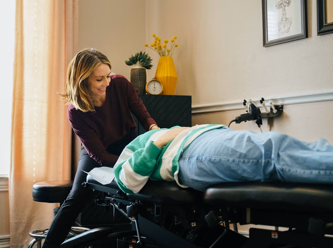 A chiropractor adjusting an adult patient on a treatment table