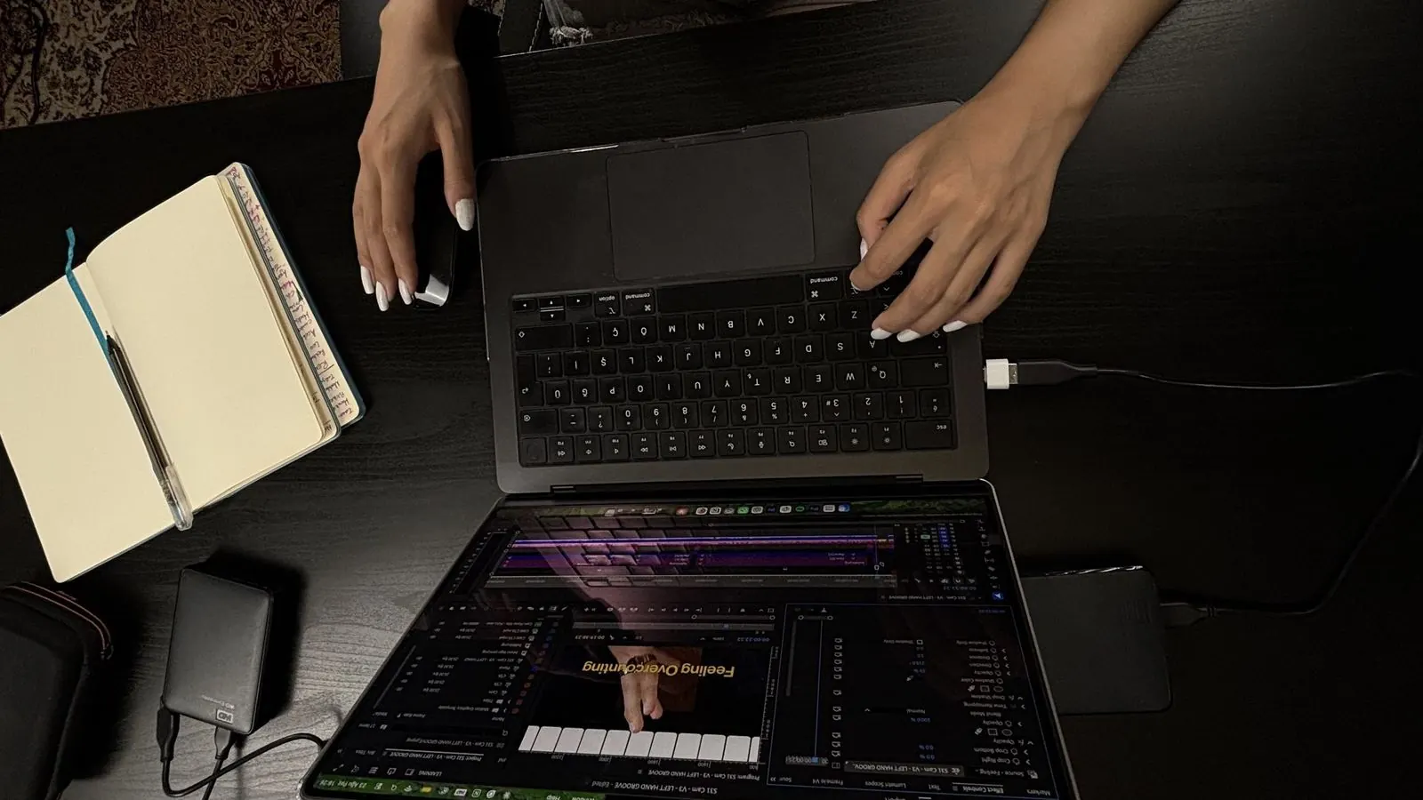 An overhead view of a laptop and notebook on a studio desk