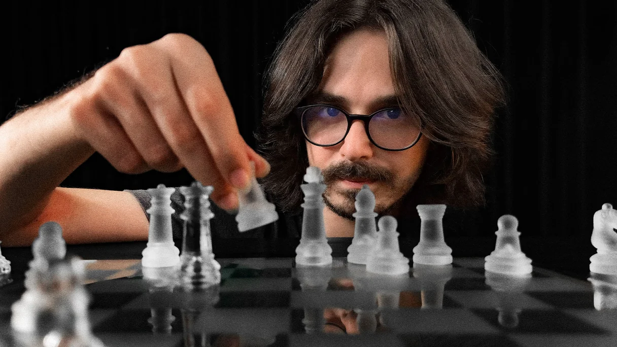 A person considering a move at a glass chess board