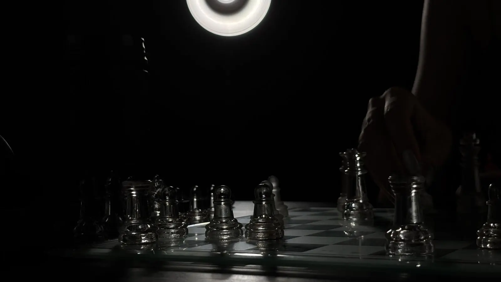 A glass chess set lit by a ring light