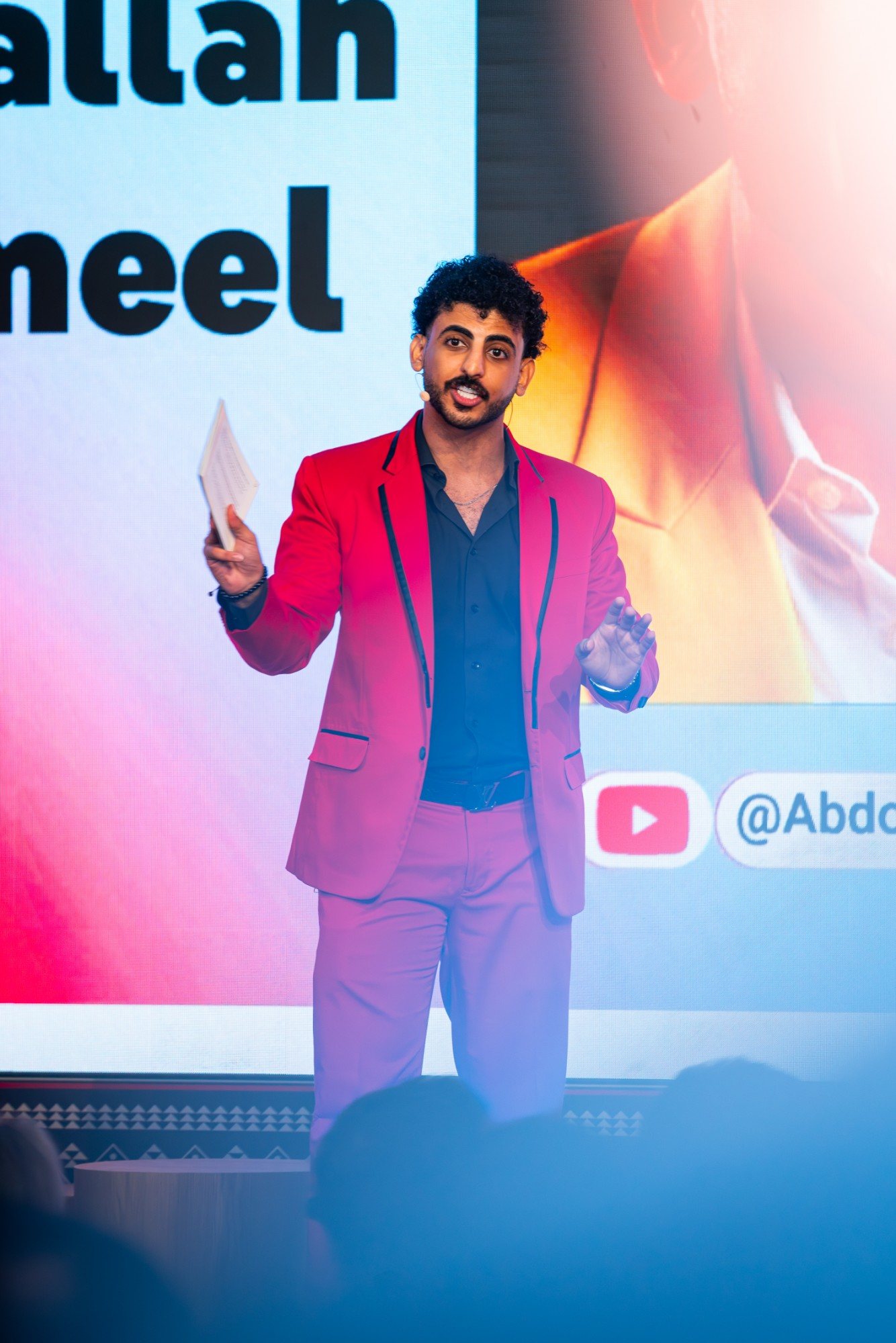 Abdullah Jamil, Abdoh4Magic, on stage in a red suit at a YouTube event