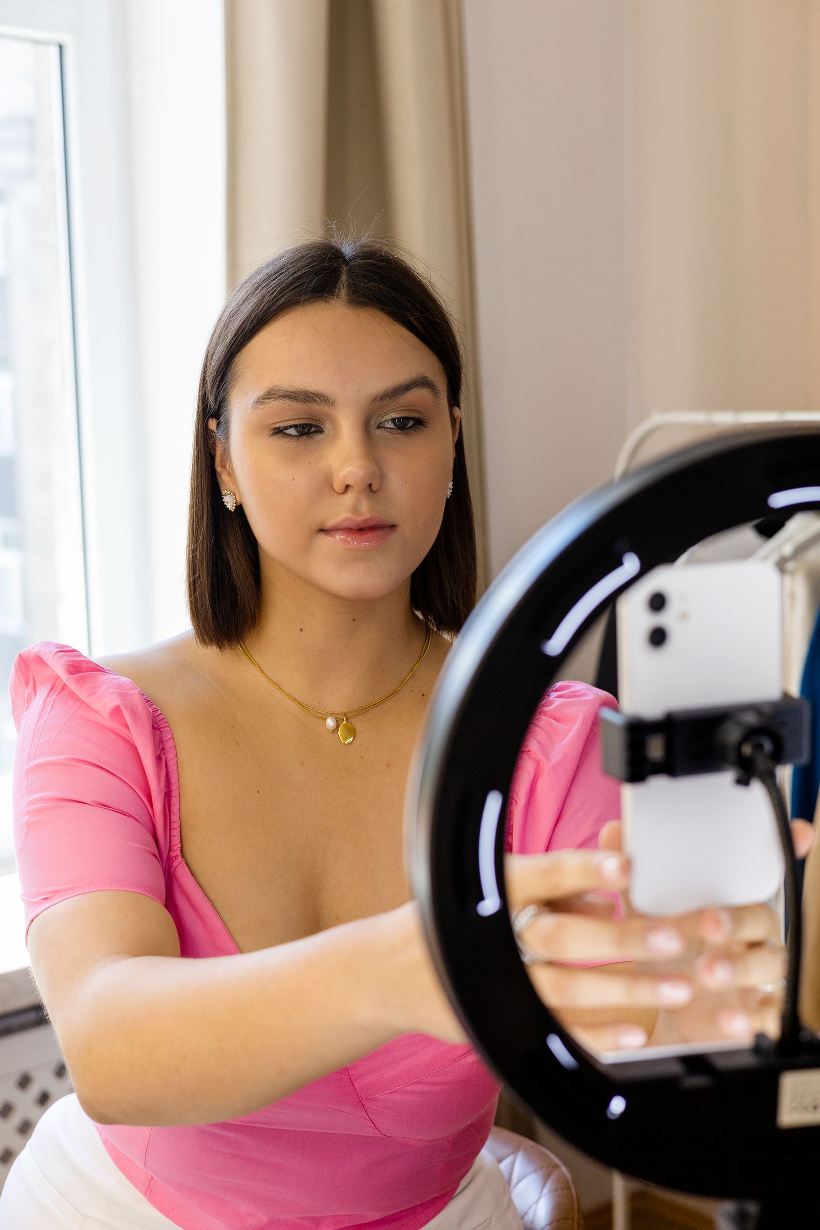 Creator filming with a phone and ring light in a colorful indoor setup