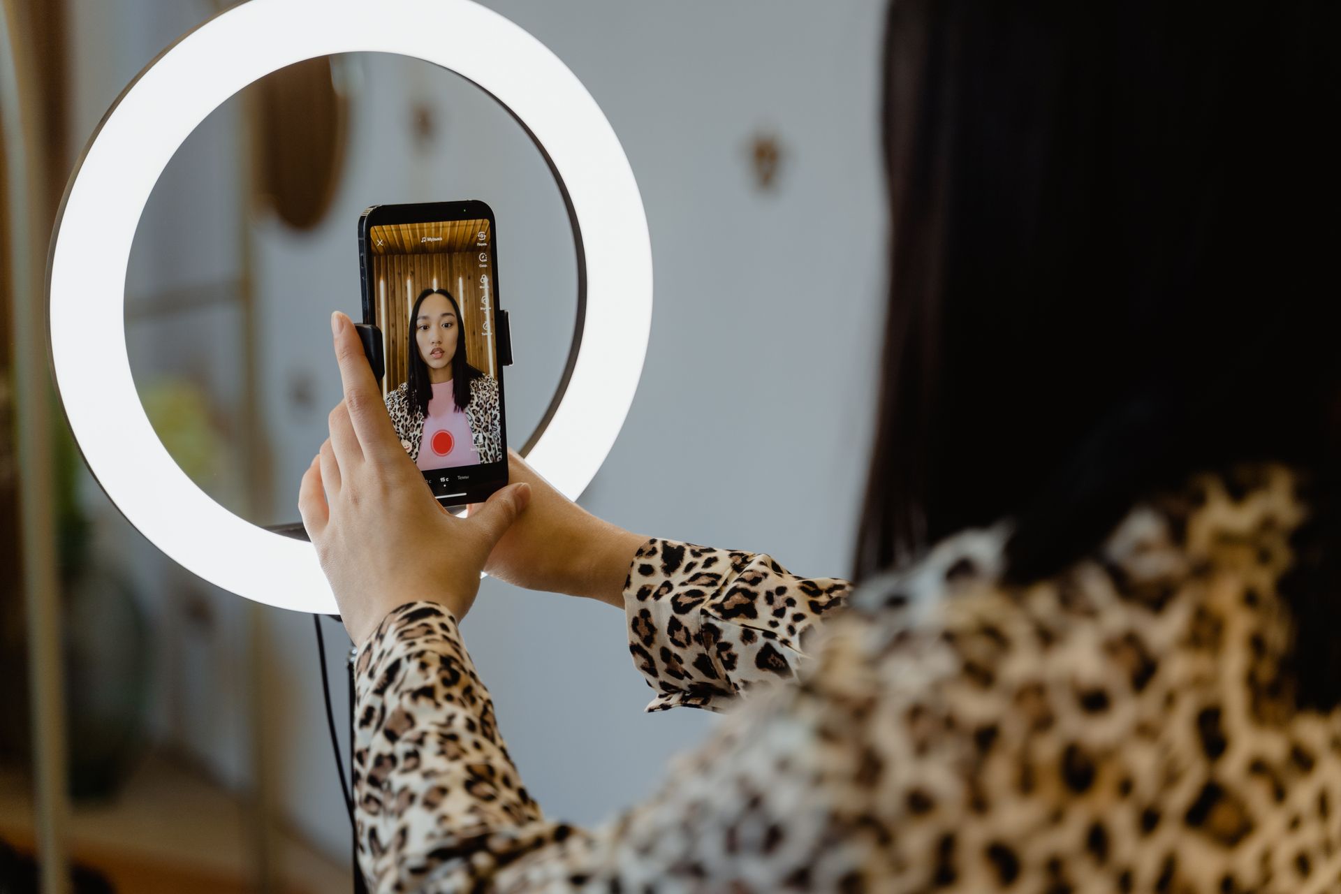 A creator filming with a smartphone on a ring light