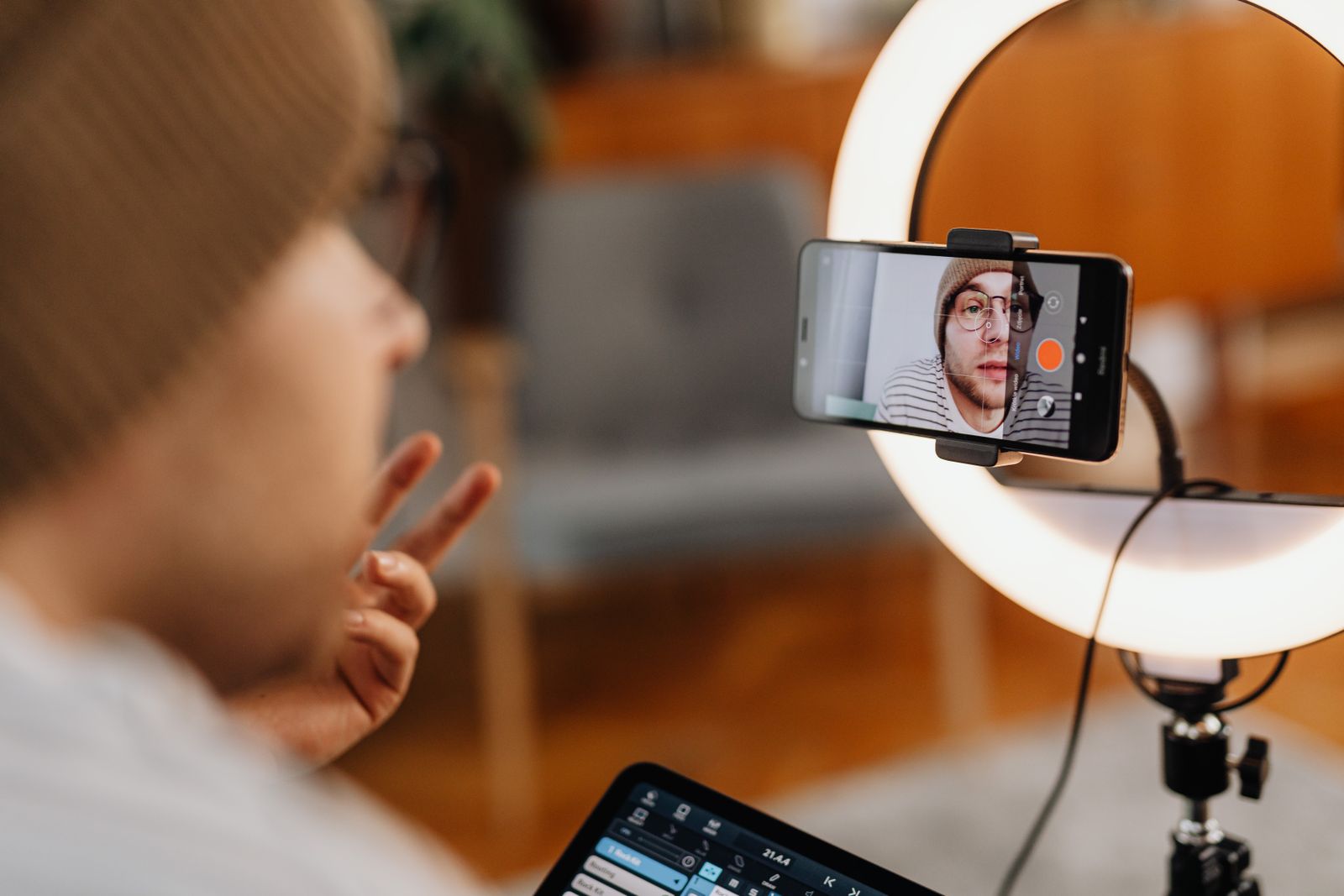 A man recording video with a ring light and smartphone indoors