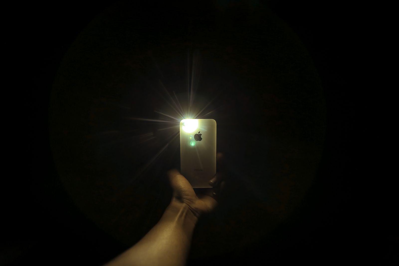 A hand holding a glowing smartphone in a dark room