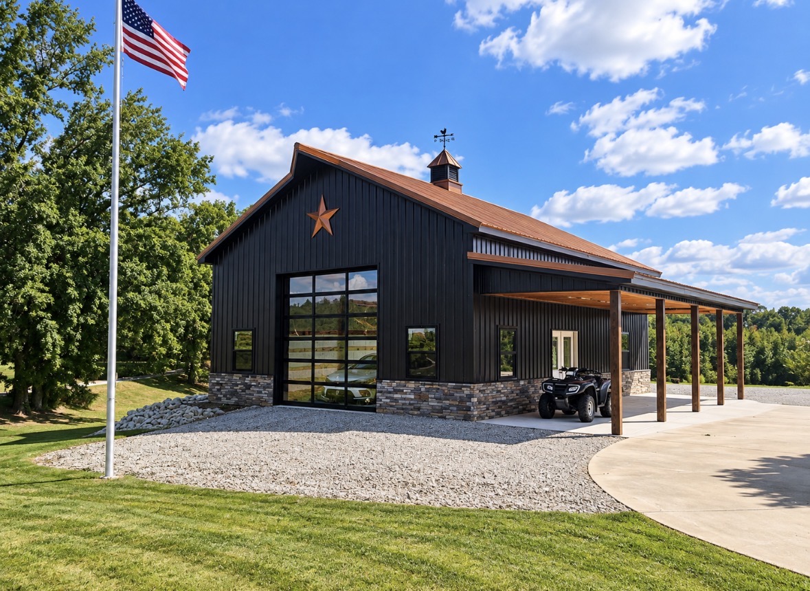 North Star barn NS-02 — black post-frame barn with stone wainscot, copper star and covered porch beside a flagpole, Middle Tennessee