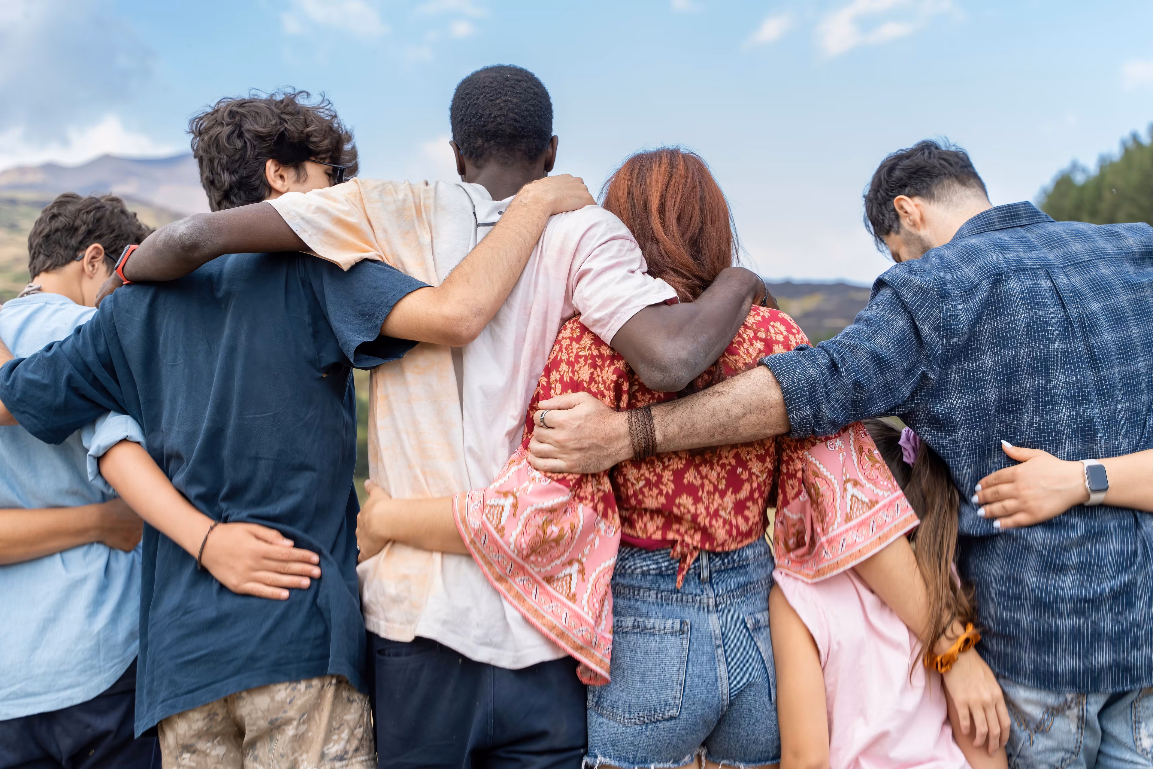 Group hug outdoors in natural light, complementary protection legal fees