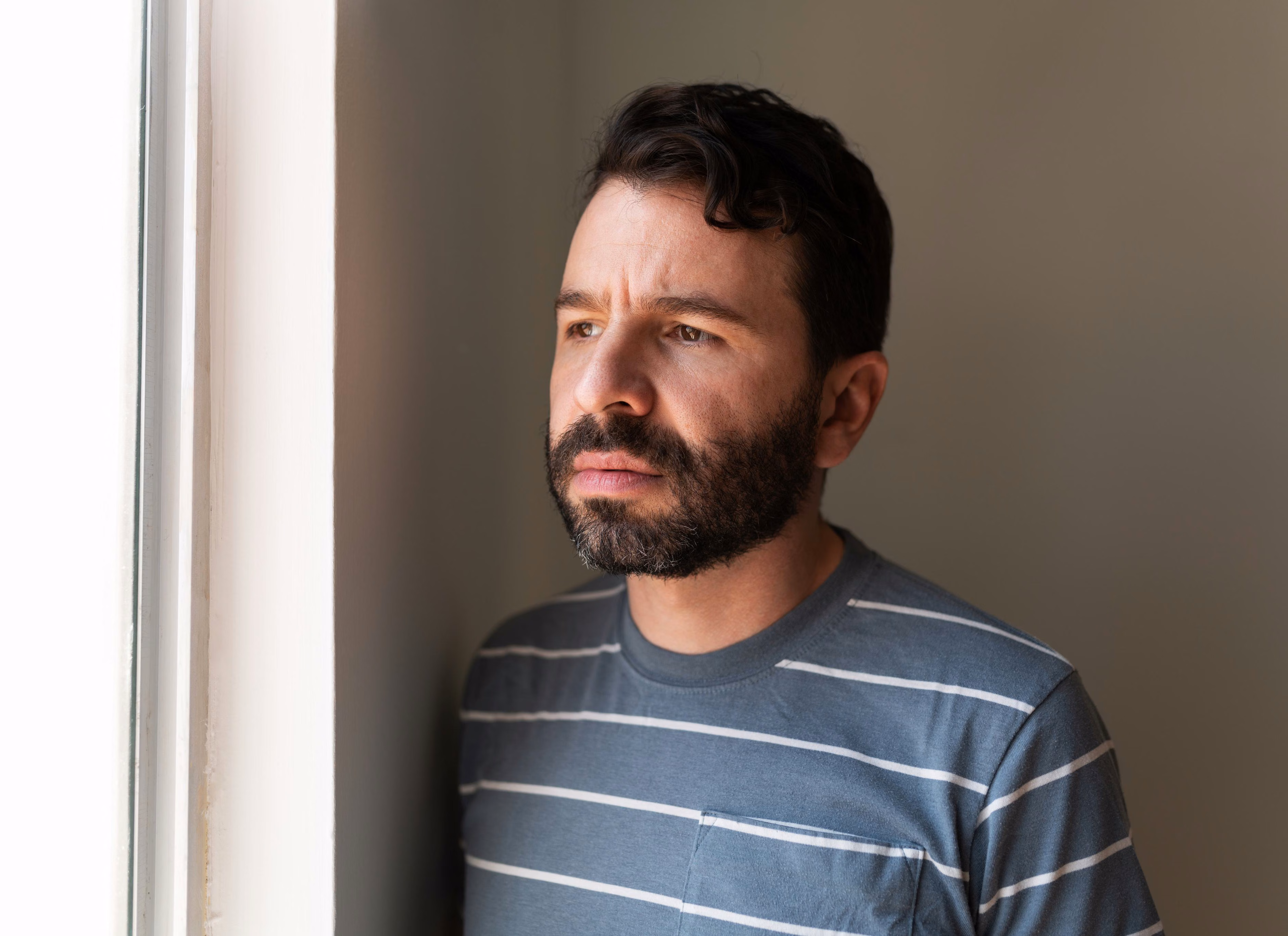 Worried man looking out of a window, visa ending before his protection visa is lodged