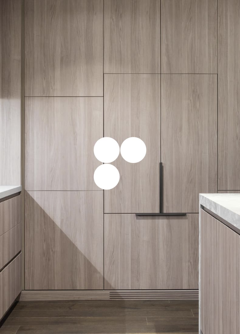 Modern kitchen with light wood cabinetry, integrated appliances, and marble countertops.