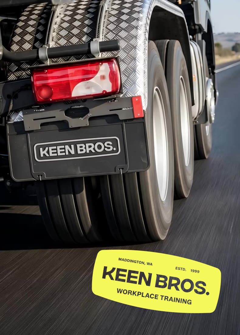 Rear wheels and mud flap of a truck with red tail light, branded Keen Bros workplace training.