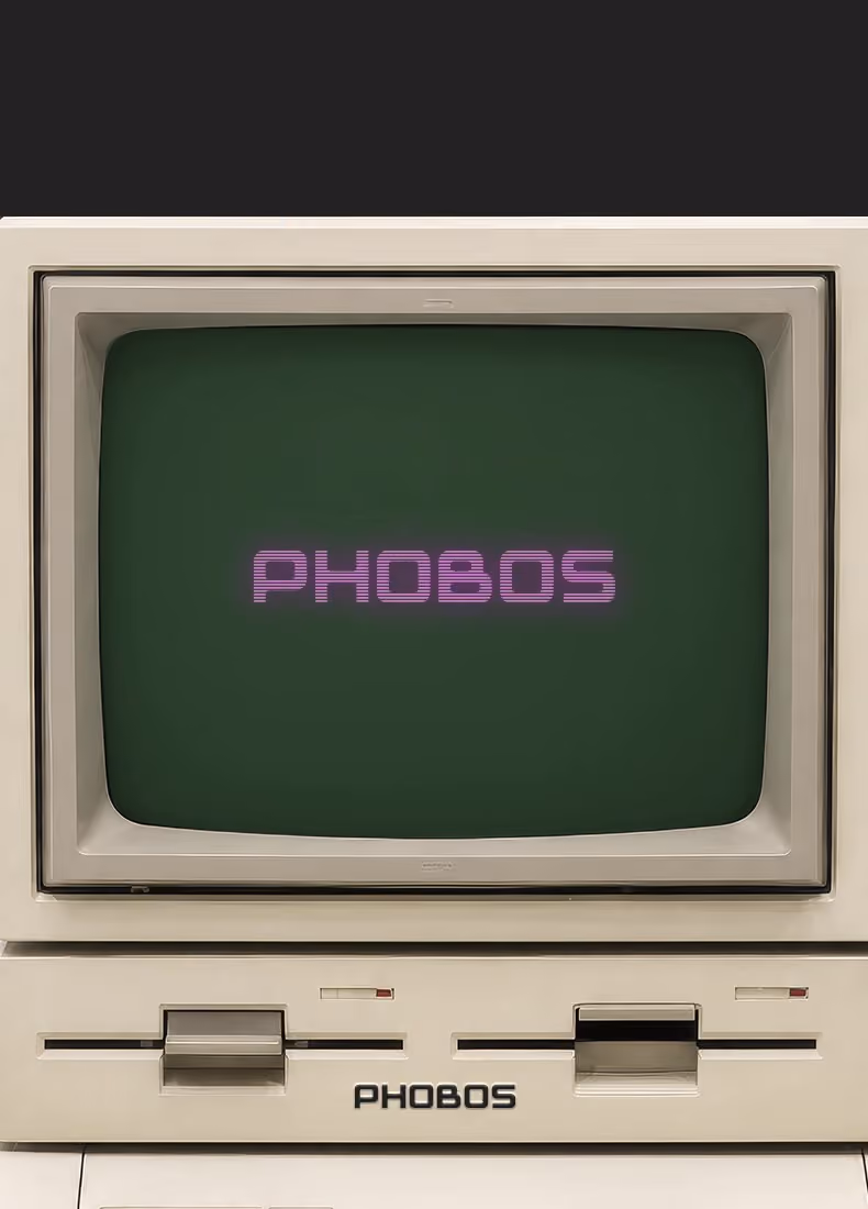 Vintage beige computer with green screen displaying the word PHOBOS in purple text.