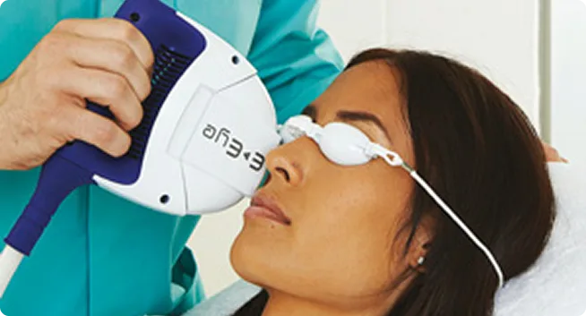 Woman wearing protective goggles receiving a laser facial treatment from a medical professional.