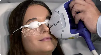 Woman undergoing eye scan with a handheld medical imaging device labeled E-Eye.
