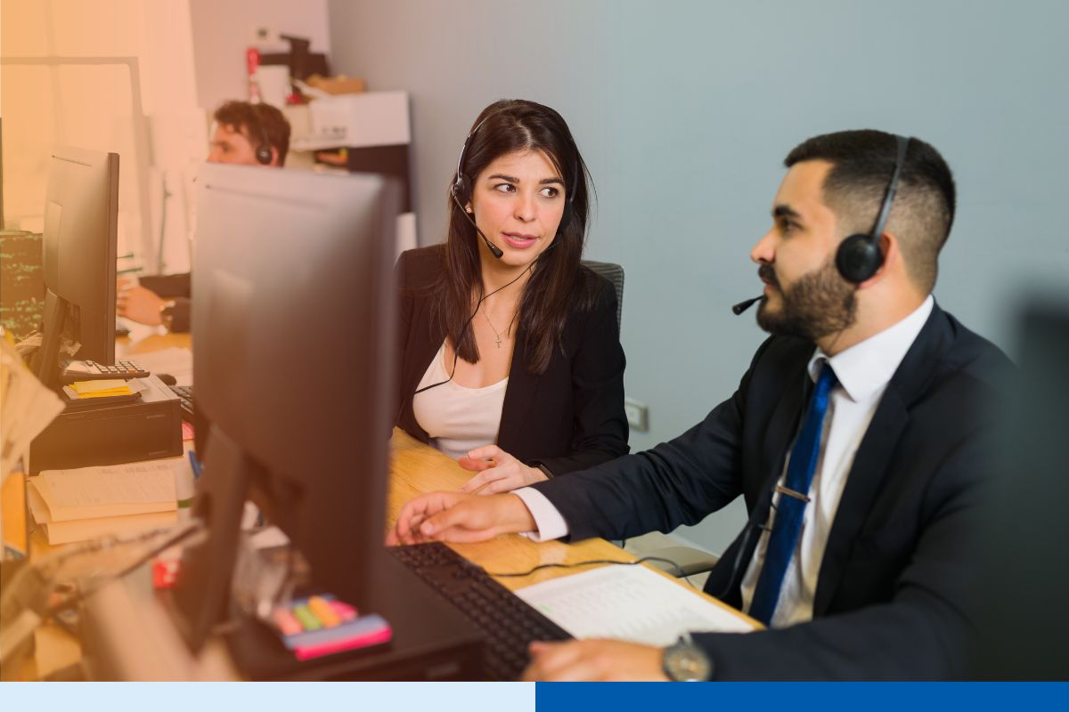 Two customer support employees taking calls and discussing