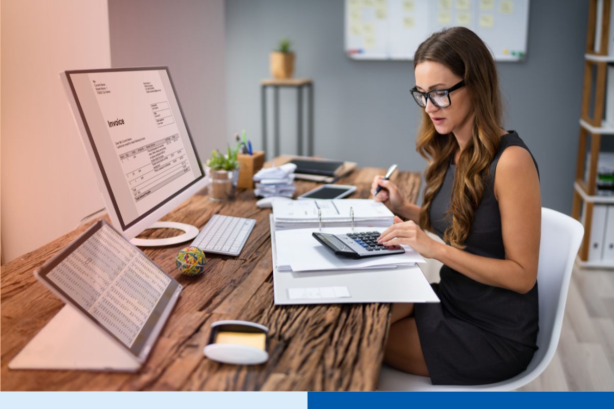 Accountant reviewing invoices and financial records on computer screens, representing services offered by remote bookkeeping companies.