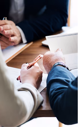 Gros plan sur des professionnels des affaires examinant et signant des documents à un bureau en bois.