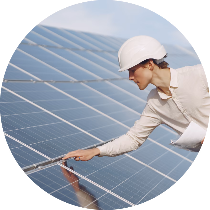 Un ingénieur portant un casque de sécurité blanc inspectant de près une installation de panneaux solaires.