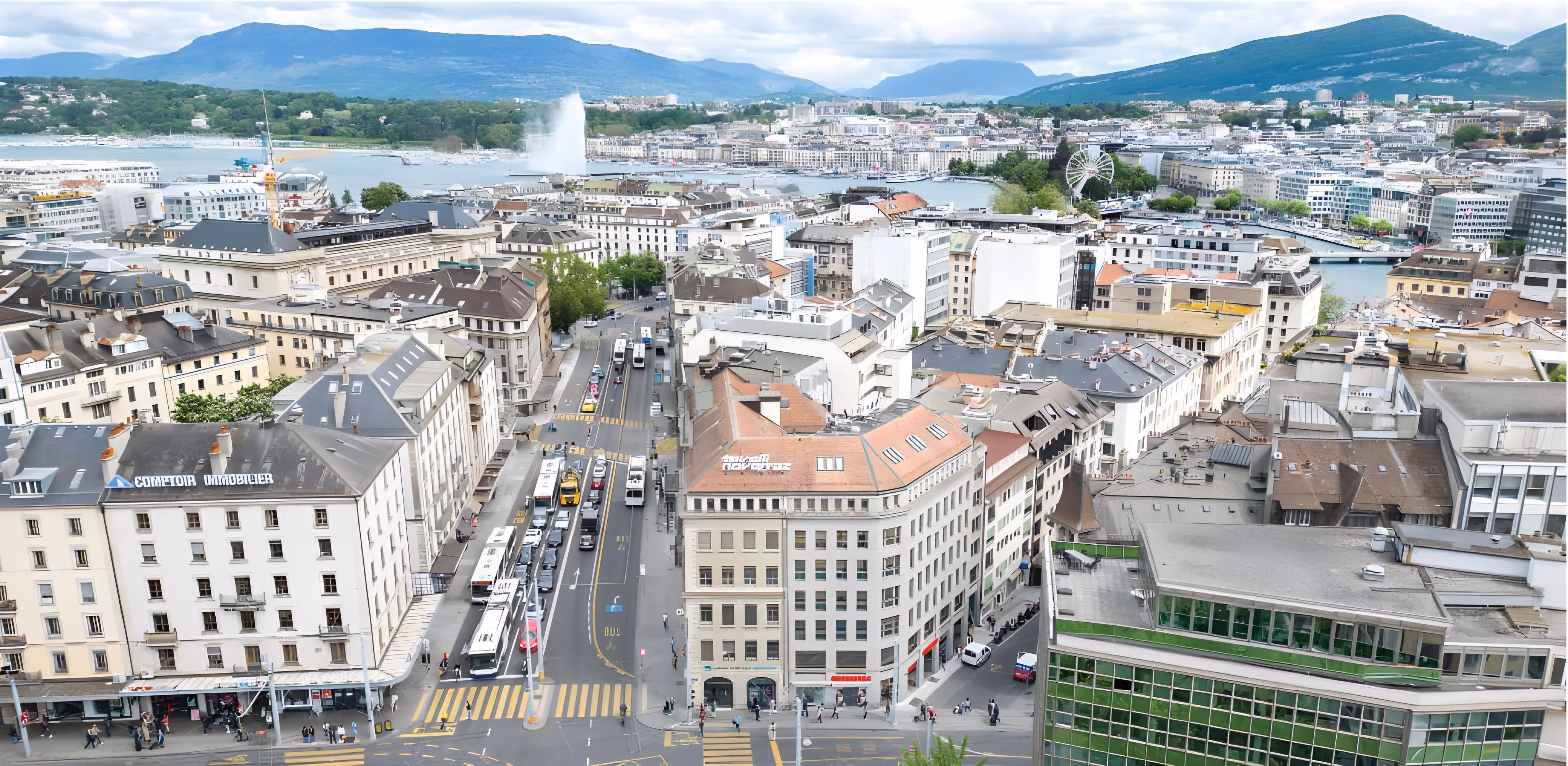 Une vue en hauteur d'une rue animée de Genève avec des transports en commun, orientée vers le lac Léman, une grande roue et le Jet d'Eau au loin.
