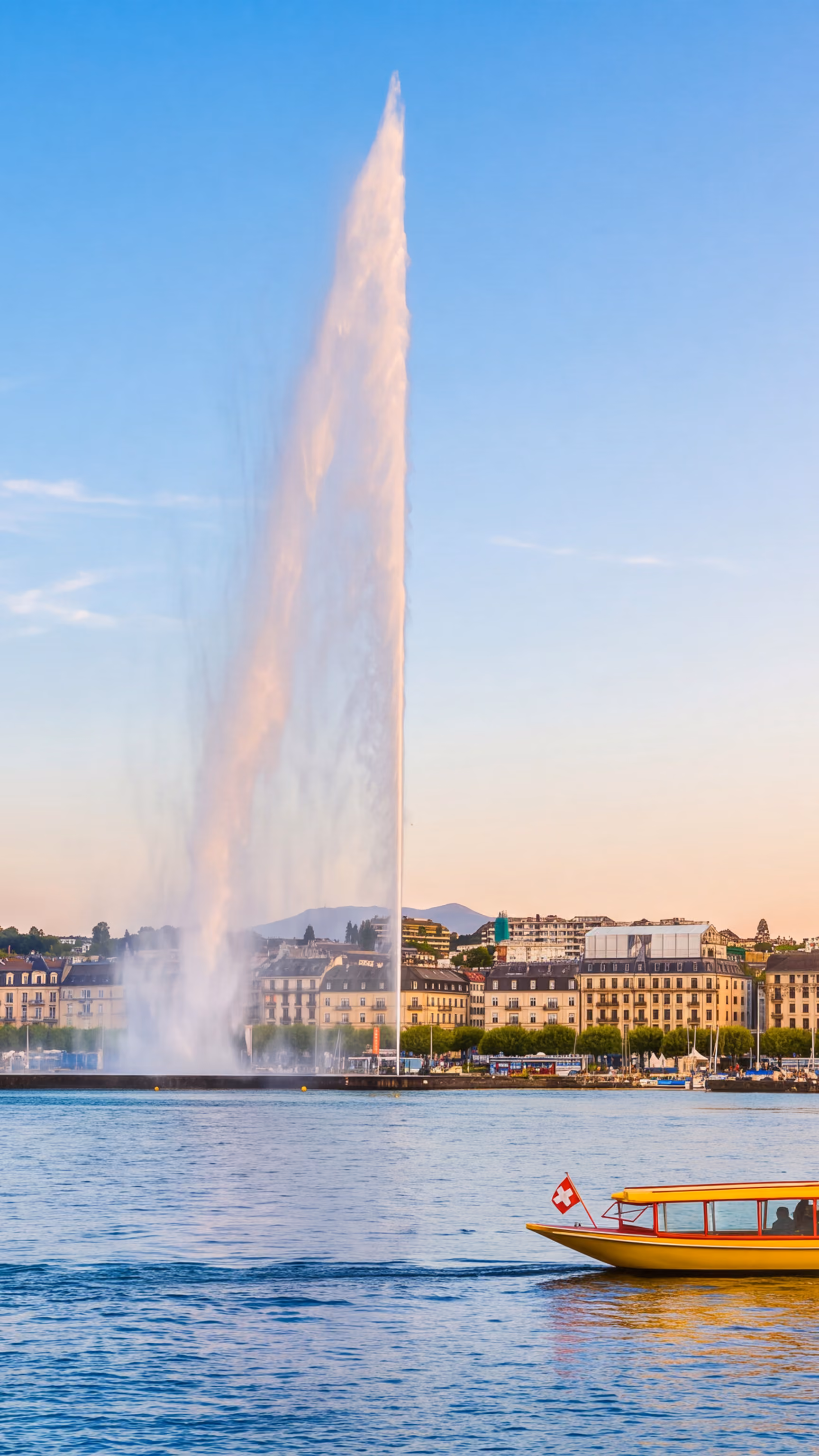 Le Jet d'Eau s'élevant au-dessus du lac Léman à Genève, avec un bateau-taxi jaune au premier plan et le panorama de la ville en arrière-plan.