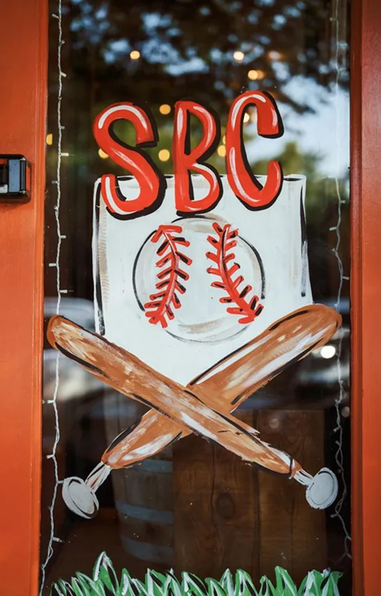 Hand-painted SBC baseball sign on a storefront window
