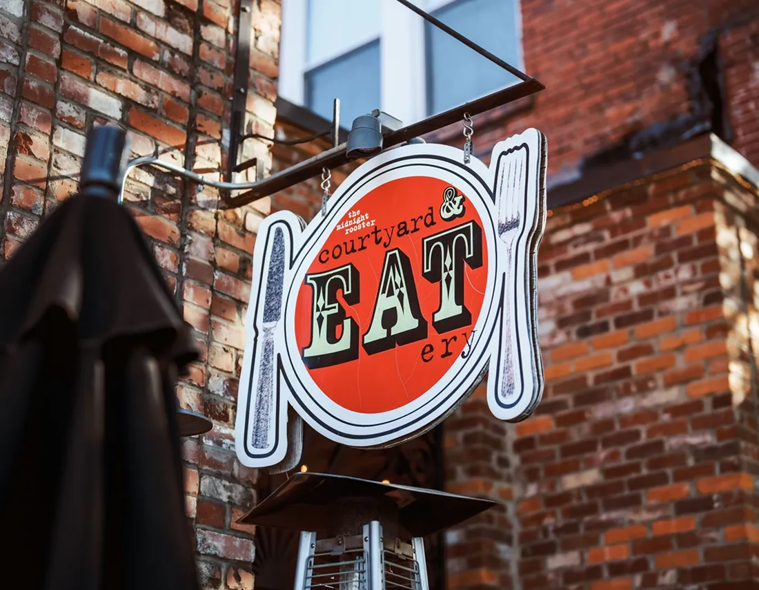 Courtyard and Eatery restaurant sign against a brick building