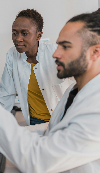 Two scientists in white lab coats working intently together in a laboratory setting.