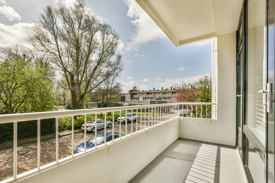 Heller Balkon eines Zimmers mit Blick auf Bäume und die ruhige Umgebung.