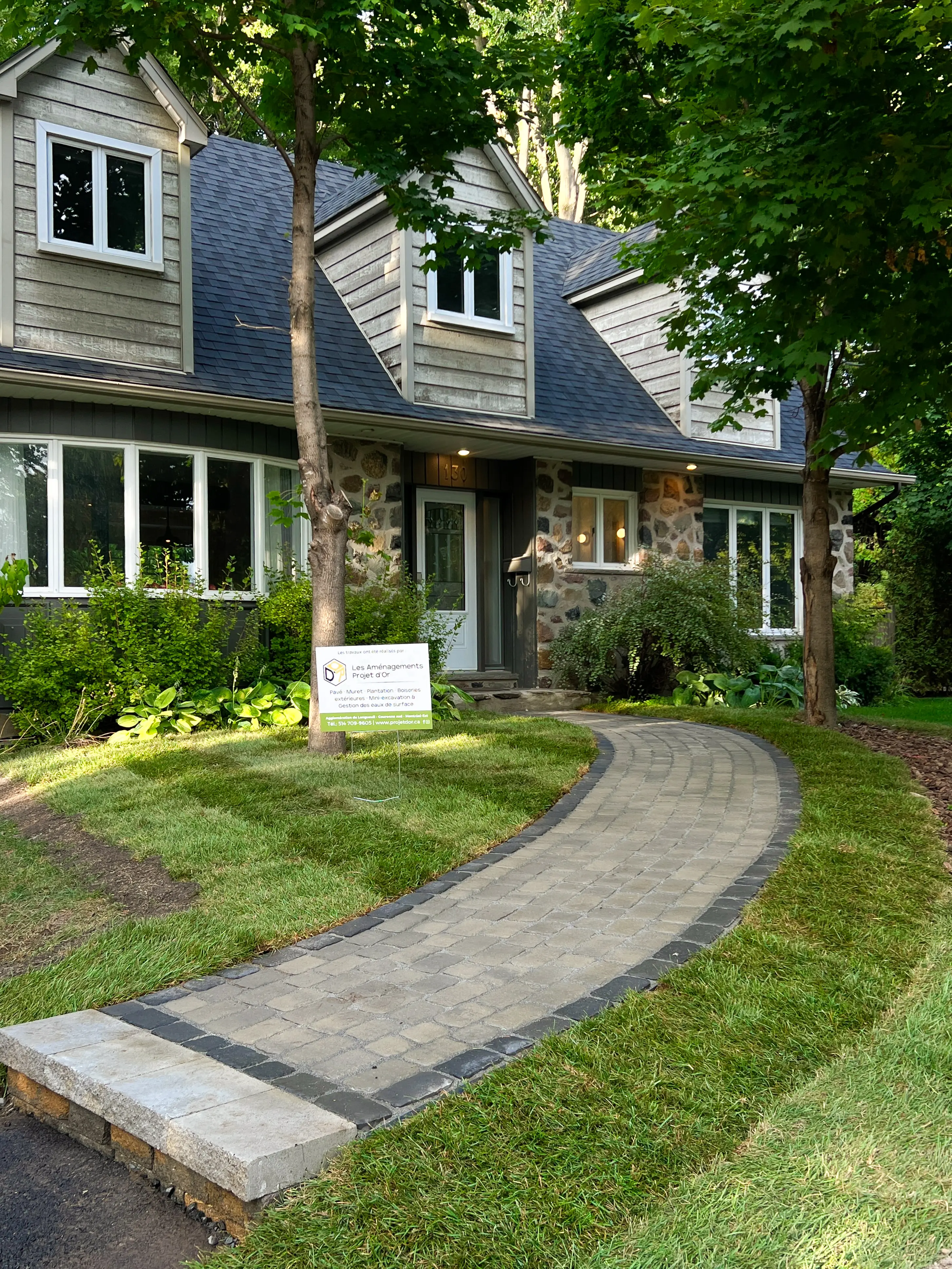 Maison en pierre avec un toit gris, bordée d’un sentier pavé menant à la porte d’entrée.