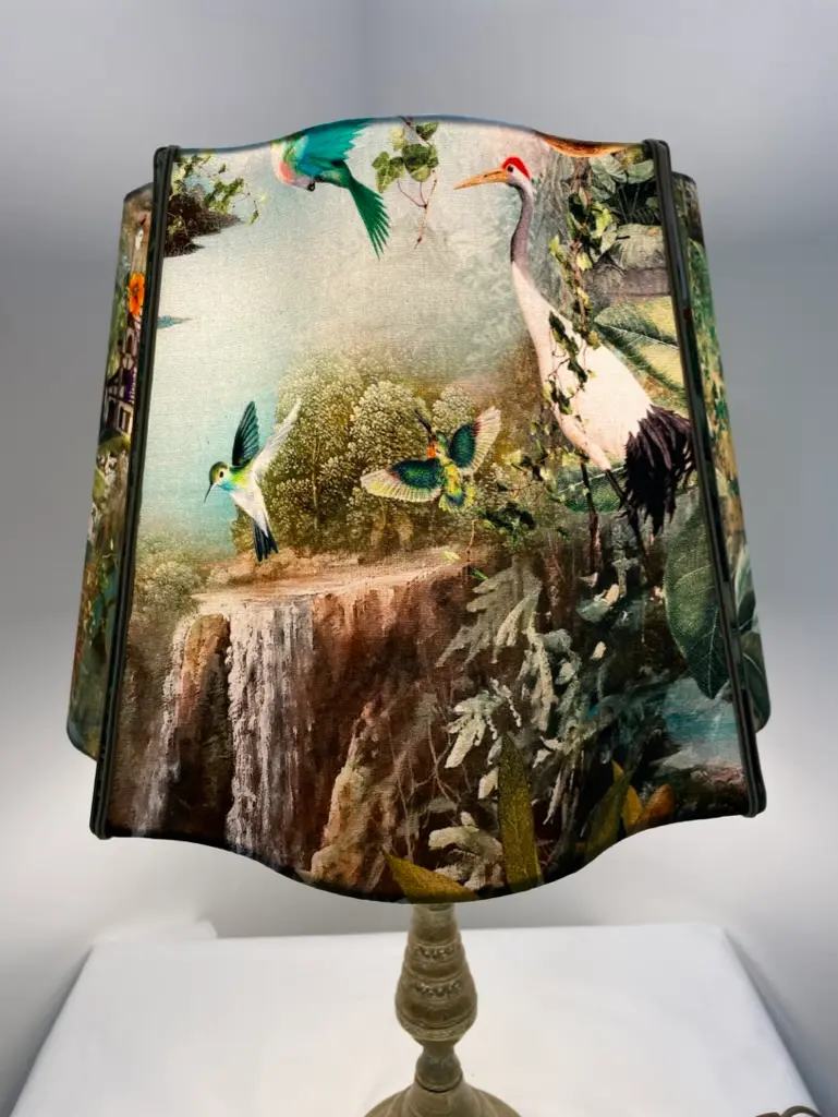 Decorative lampshade featuring birds, greenery, and a waterfall scene on fabric.