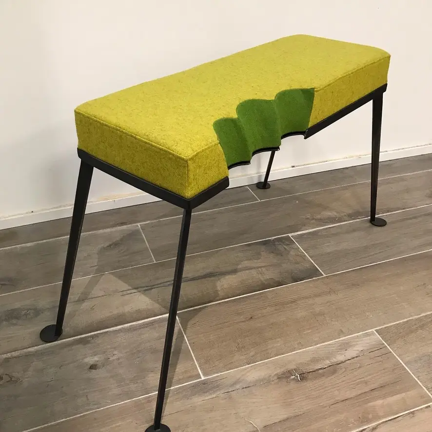 Modern bench with black metal legs and green cushioned seat featuring a scalloped cutout design.