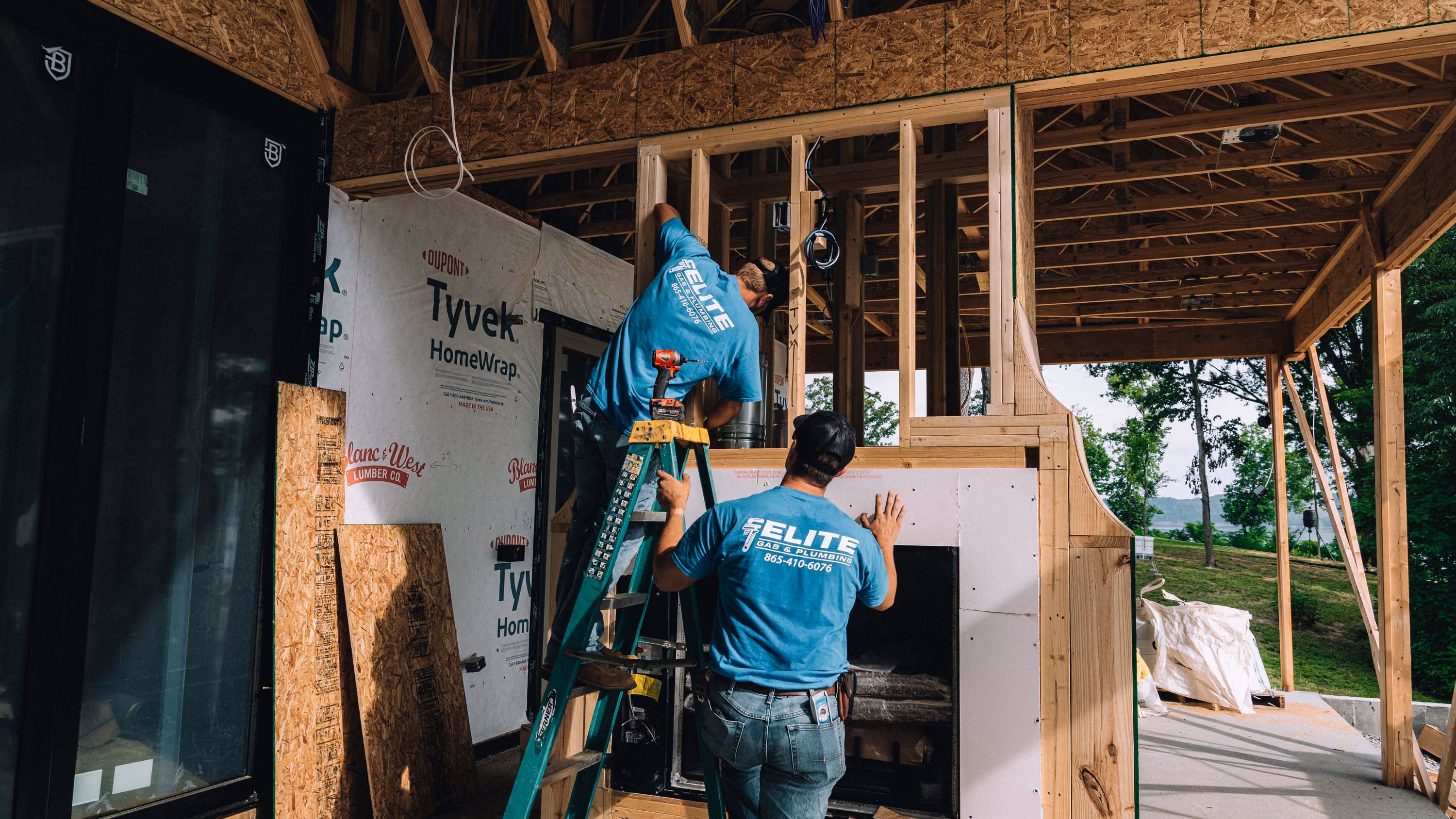 Workers inside a wooden structure installing plumbing in new construction.