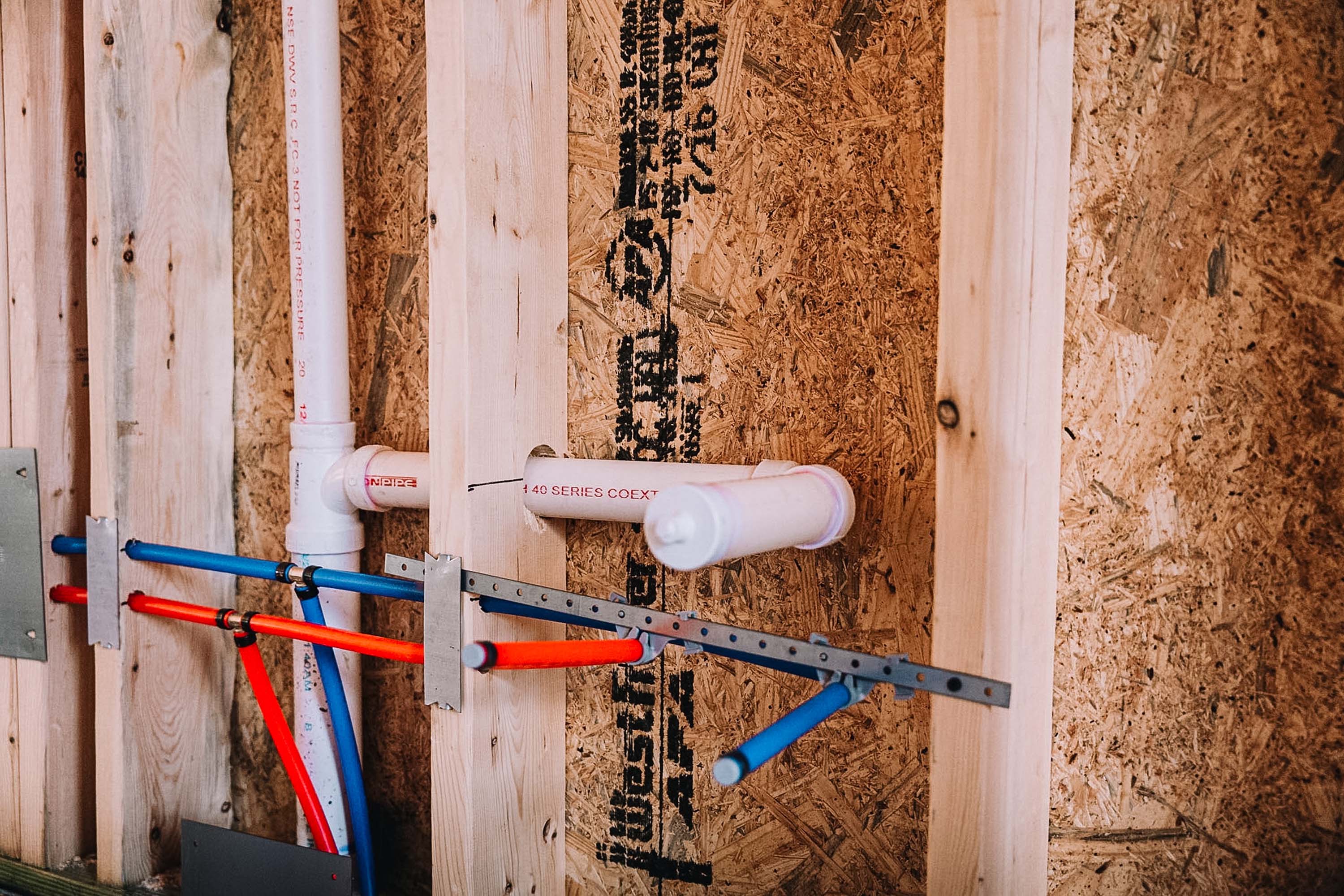 Plumbing pipes run across plywood sheeting in a construction setting.