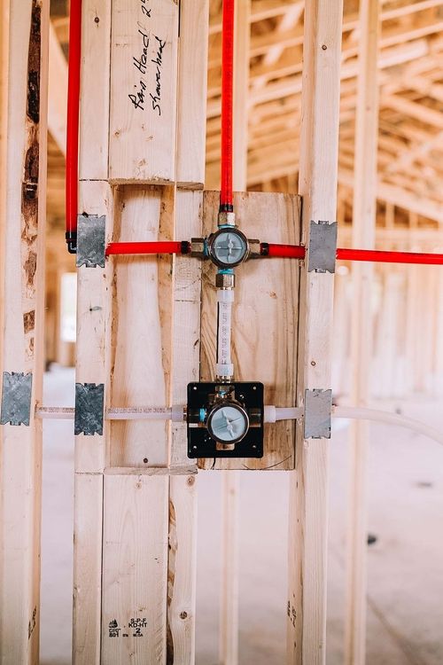 Gas and water lines fitted to vertical wood studs in new construction plumbing.